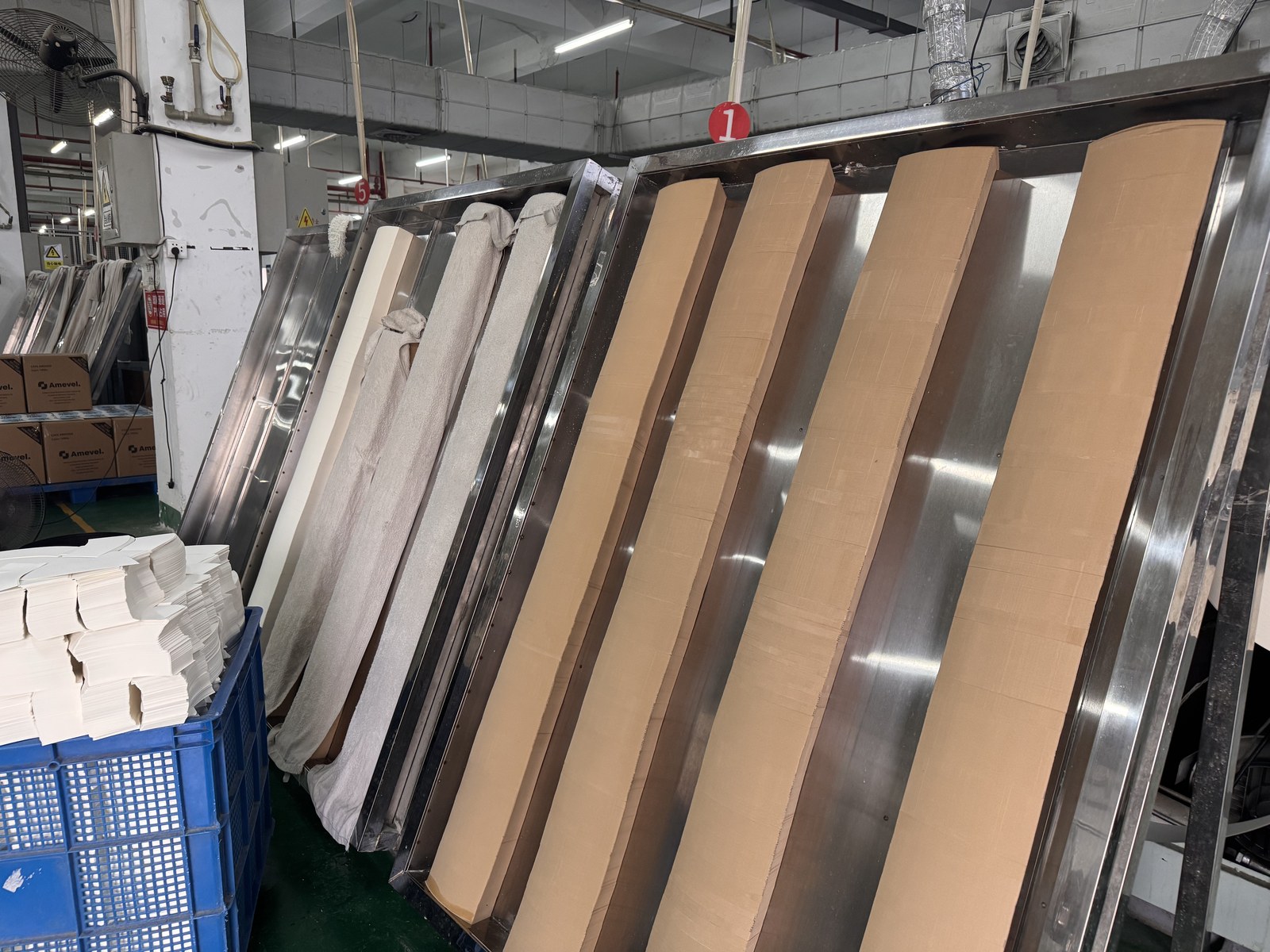Paperboard blanks staged beside forming equipment in a factory workshop
